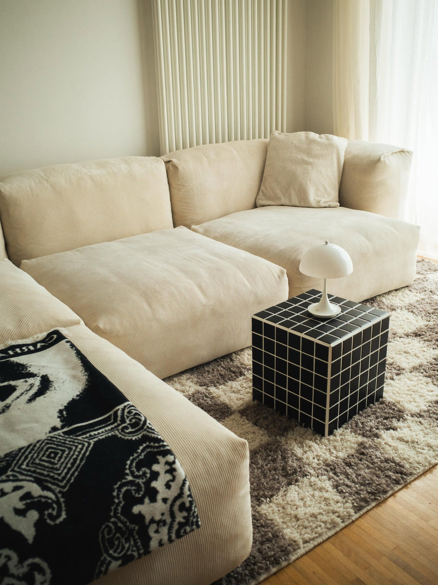 Canapé modulable Cloud en tissu écru avec coussins de dossier, table cube à carreaux noirs et tapis moelleux