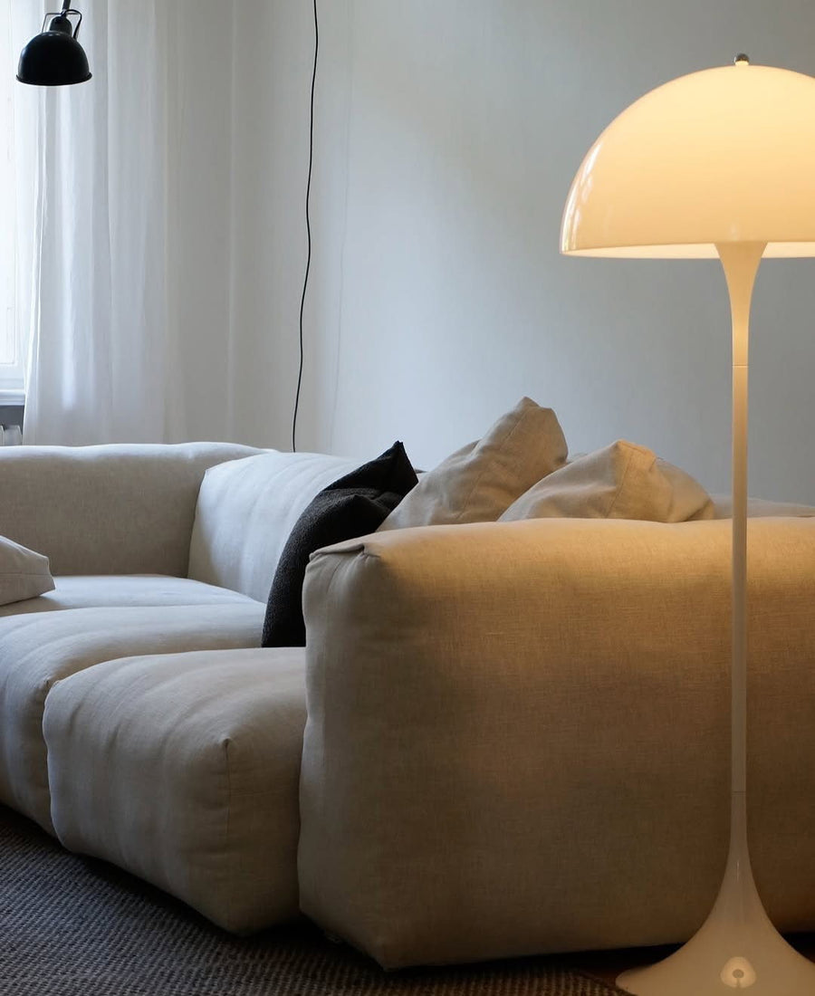Fauteuil Cloud en tissu bouclé écru avec coussin noir et lampadaire champignon dans un salon épuré