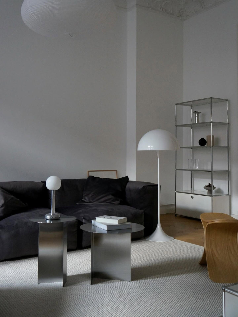Canapé modulable Cloud en tissu noir avec tables d’appoint chromées, lampadaire blanc et étagère métallique