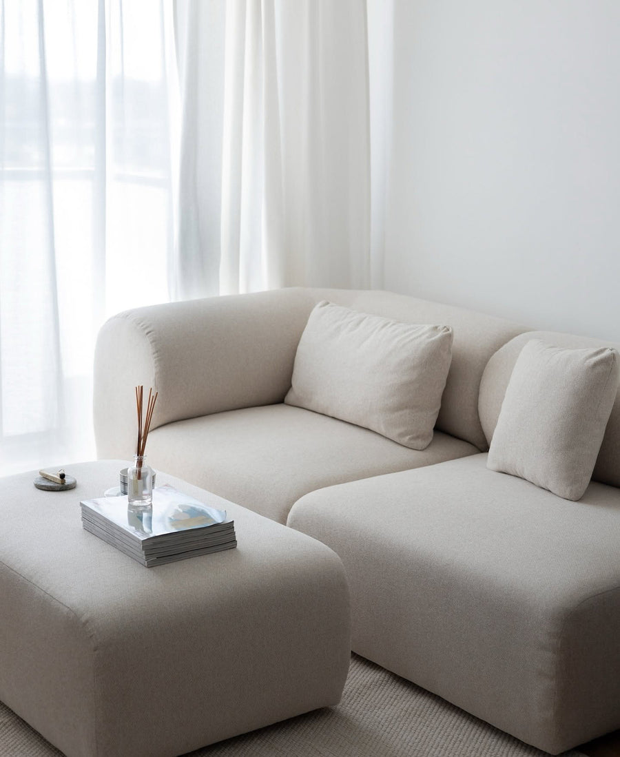 Canapé modulable Hug en tissu bouclé écru avec pouf, coussins et plateau devant de grands voilages