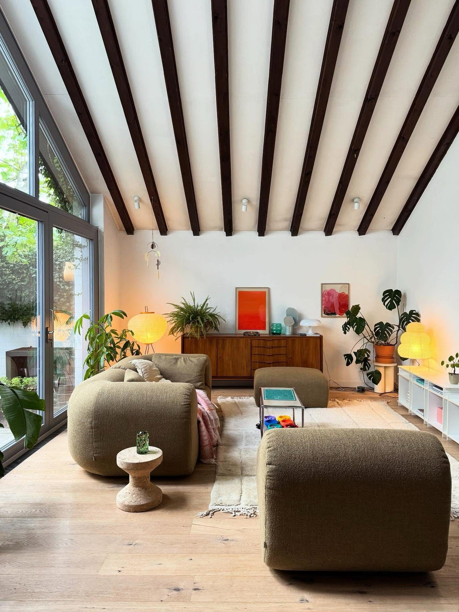 Canapé modulable Hug en tissu vert olive avec pouf et tabouret en liège sous un plafond à poutres apparentes