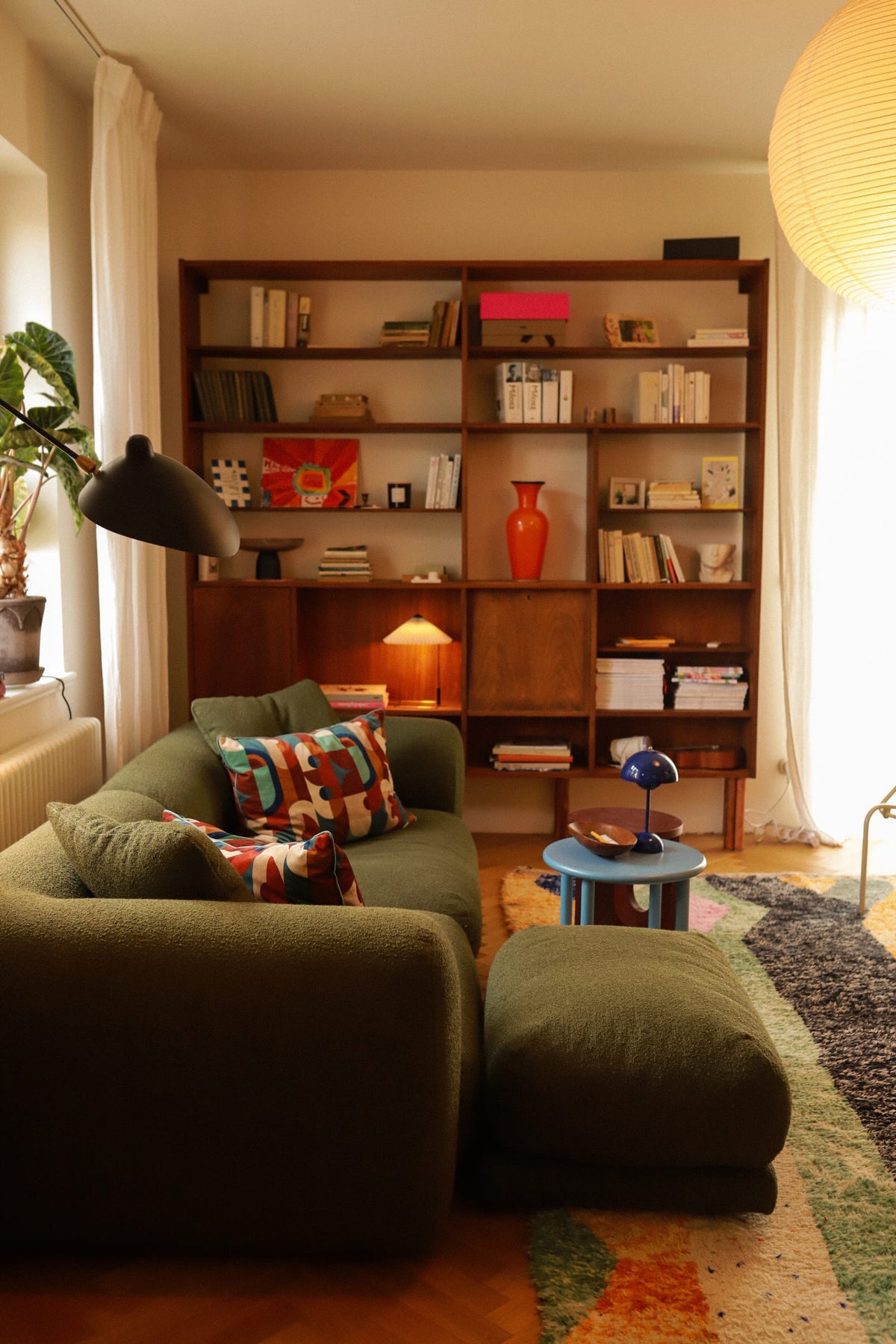 Canapé modulable Lazy en bouclette vert olive avec pouf, dans un salon chaleureux