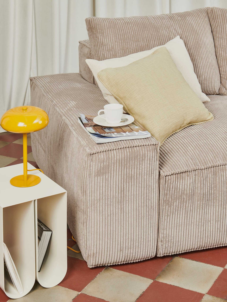 Accoudoir et coussin du canapé modulable Loft en velours côtelé beige, avec lampe jaune et tasse de café
