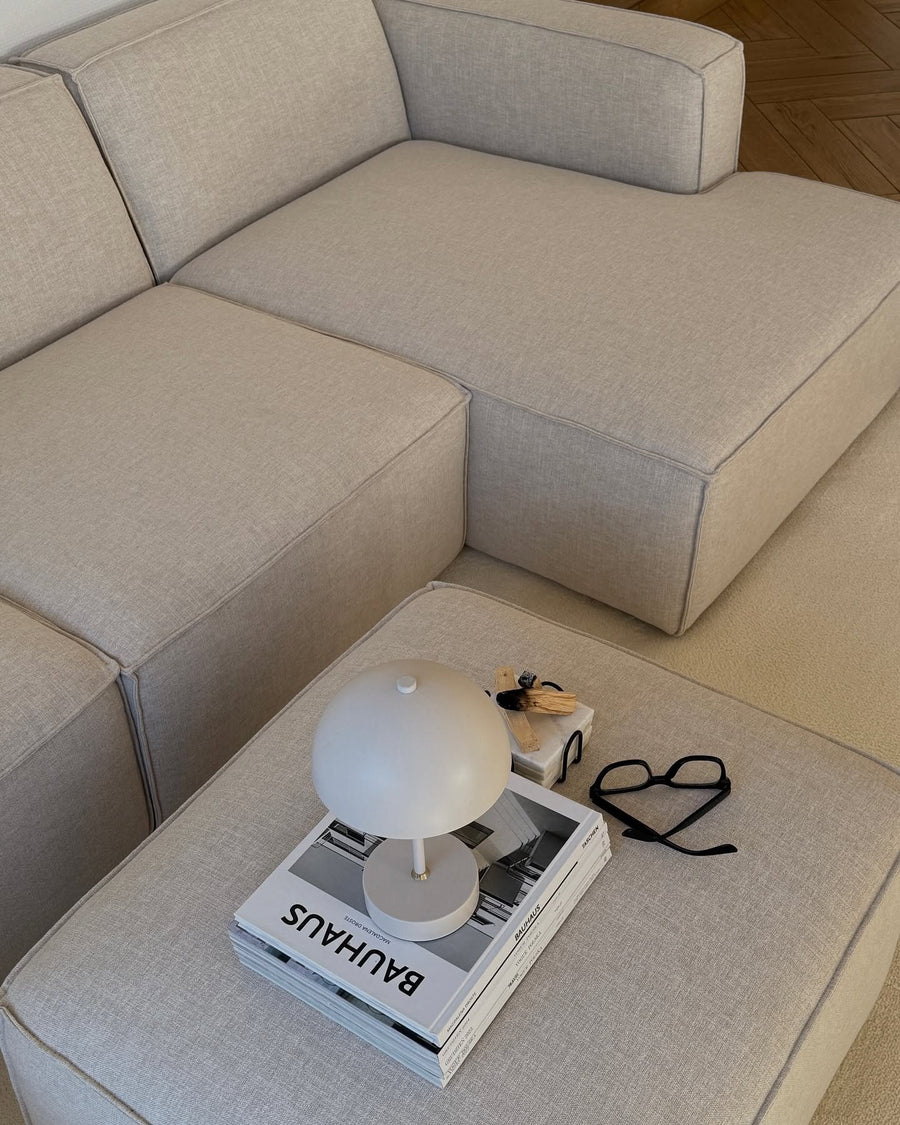Pouf et assise du canapé modulable Slay en tissu gris clair, avec lampe champignon, lunettes et livres