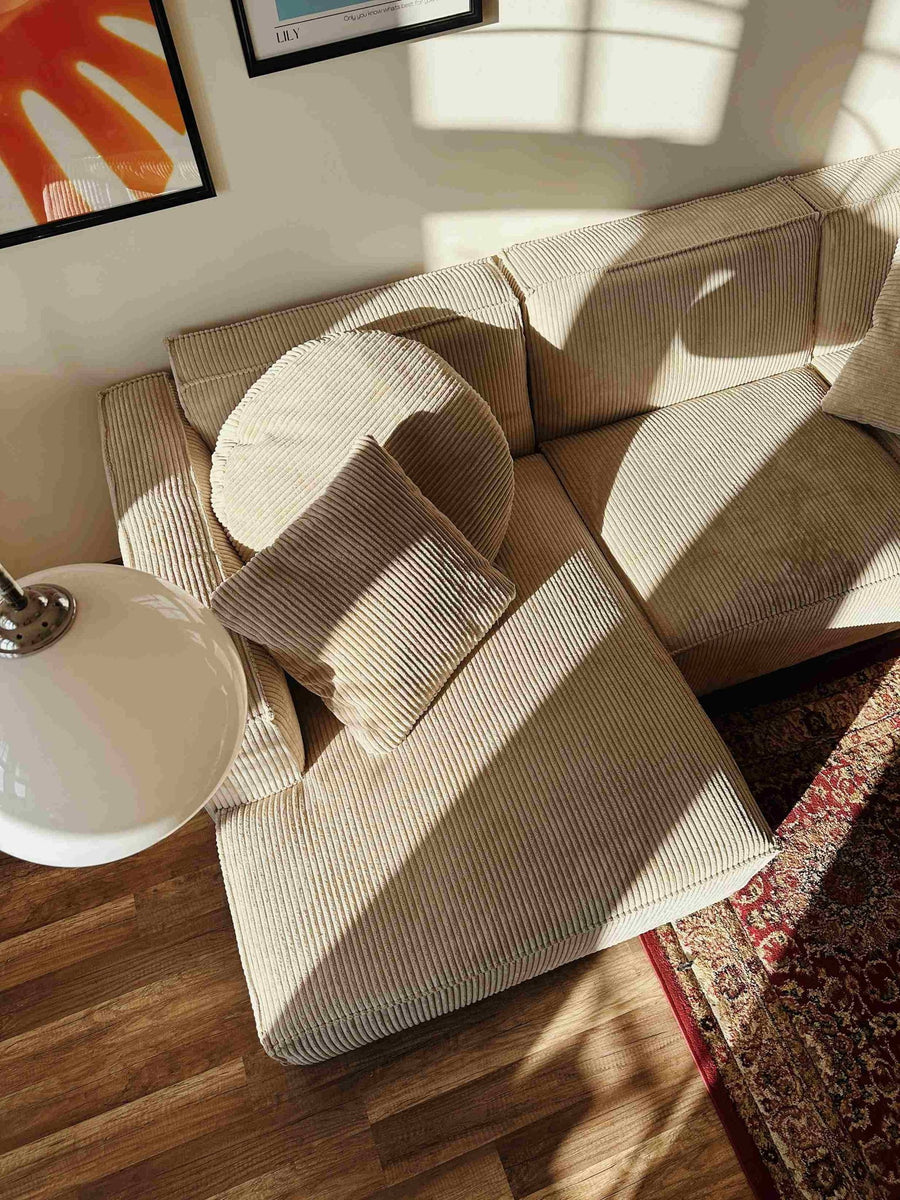 Coussins et modules du canapé Slay en velours côtelé beige au soleil, sur parquet et tapis persan